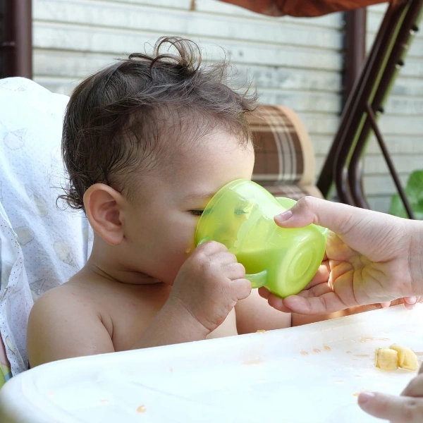 Image of a toddler drinking a smoothie with vegan greens powder.