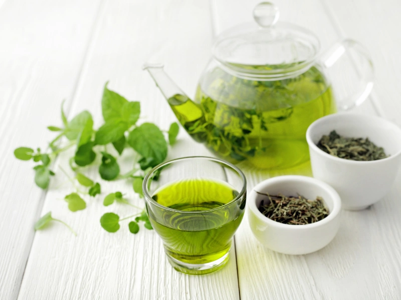Image of a cup of green tea and tea leaves.